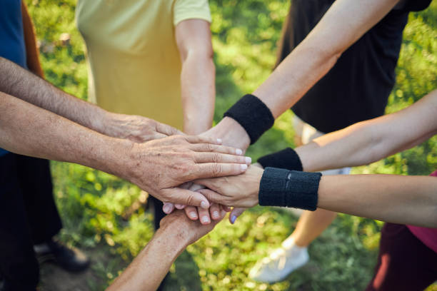istock Group of exercising seniors stacking hands together outdoors 1270837447