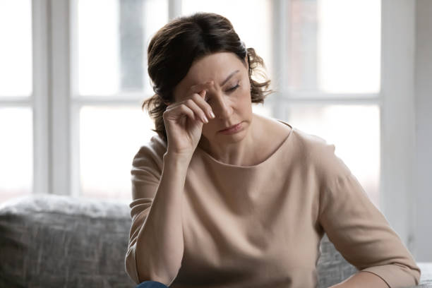 Stressed middle aged woman worrying about hard life situation. Stressed middle aged brown haired woman worrying about hard life situation, feeling unwell alone at home. Unhappy older lady mourning, suffering from negative thoughts or loneliness indoors. Perimenopause stock pictures, royalty-free photos & images