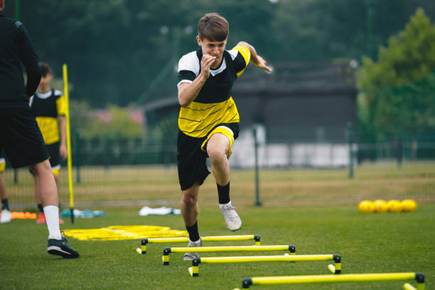 Soccer player running fast and ladder skipping. Teenagers on soccer training camp. Boys practice football witch young coach. Junior level athletes improving soccer skills on outdoor training Soccer player running fast and ladder skipping. Teenagers on soccer training camp. Boys practice football witch young coach. Junior level athletes improving soccer skills on outdoor training sports training drill stock pictures, royalty-free photos & images