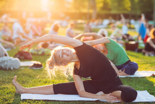 A group of young people do yoga in the Park at sunset. stock photo