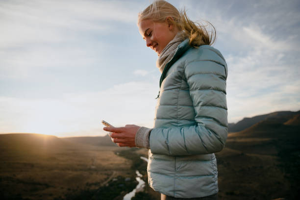 istock Blonde caucasian female scrolling on smartphone while hiking down mountain at sunset 1270844226