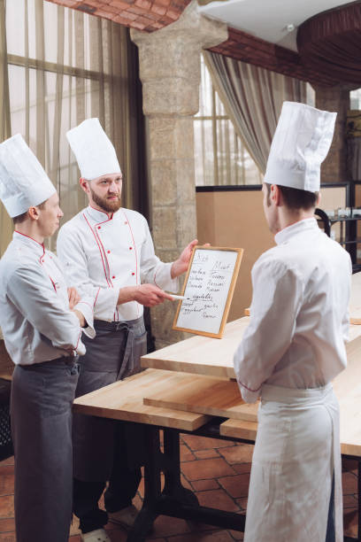 istock Head Chef and his staff in kitchen. interacting to in commercial kitchen 1270846913