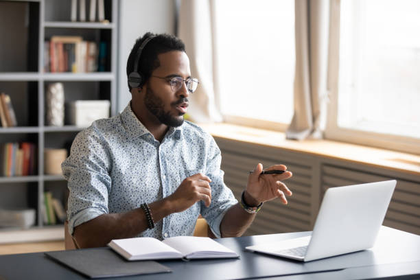 istock African American man wearing headphones speaking, using laptop 1270850618