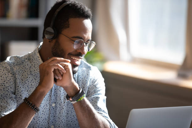istock Smiling African American man wearing headphones speaking, using laptop 1270850623