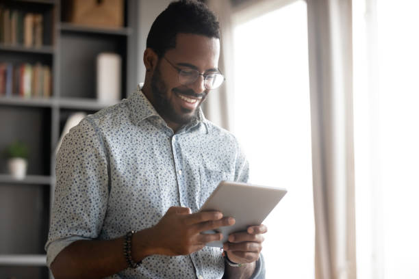 istock Smiling African American man holding computer tablet, looking at screen 1270850751