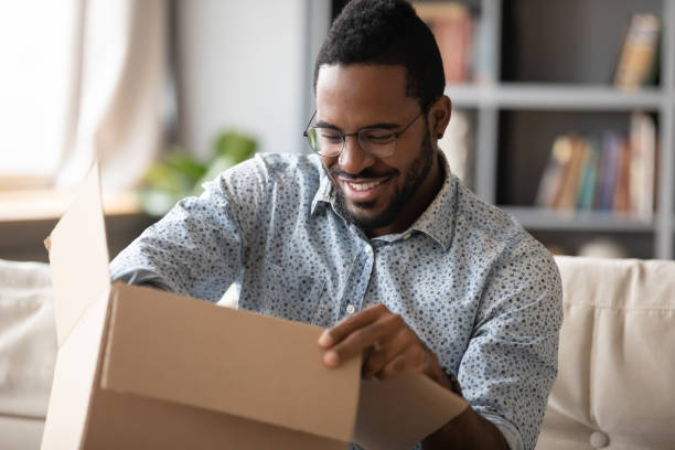 istock Smiling African American man wearing glasses unpacking parcel 1270851172