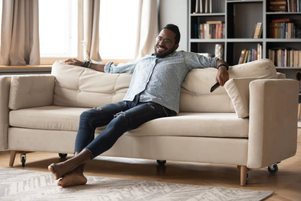 istock Smiling African American man relaxing on couch, watching tv show 1270851186