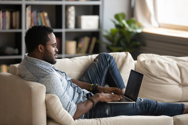 istock Confident African American man lying on couch, using laptop 1270851191