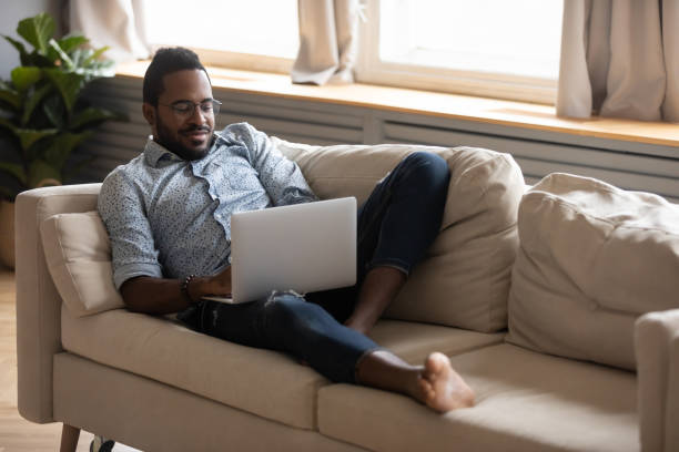 istock Satisfied African American man relaxing on couch, using laptop 1270851193