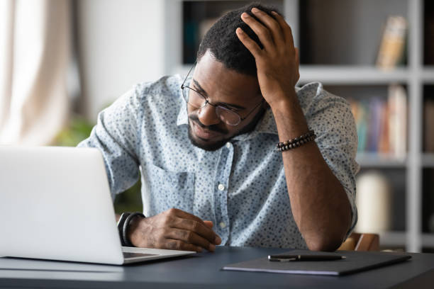 istock Upset stressed African American businessman using laptop, touching head 1270851195