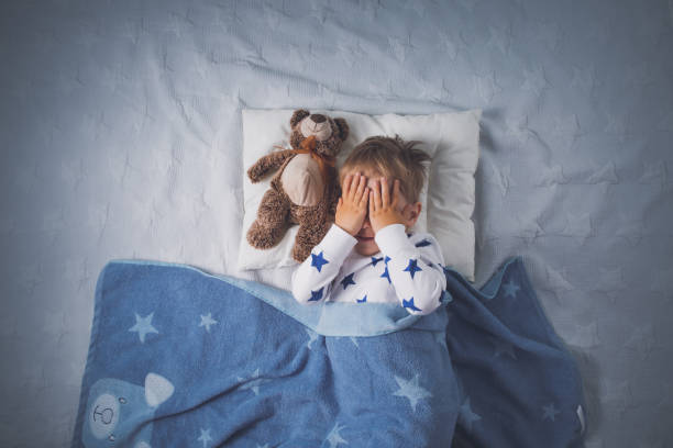 Three years old child crying in bed Three years old child crying in bed. Sad boy on pillow in bedroom plush bear stock pictures, royalty-free photos & images