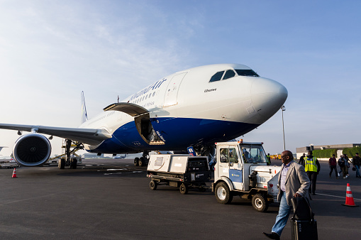 Kigali, Rwanda, October 5th 2018: A disembarking passenger walks past one of Rwandair's two wide-bodied Airbus A330 aircraft at Kigali airport. The plane had just landed from Brussels. \nThis plane is an Airbus A330-200 named Ubumwe, which in the local Kinyarwanda language means ‘Unity.’