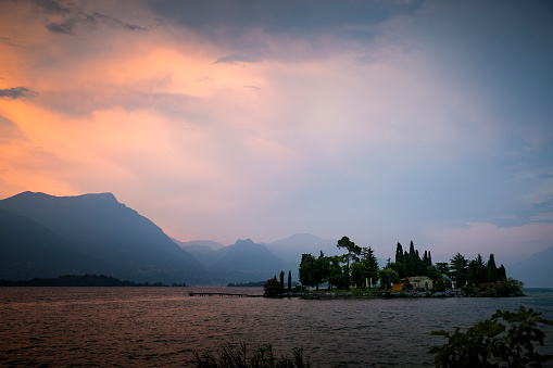 View of Garda Lake and San Biagio island at pink and blue misty sunset in Manerba del Garda, Italy.