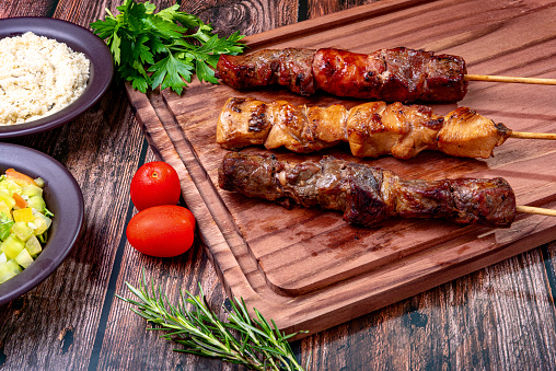 Kebab - Grilled meat on a cutting board, with flour and vinaigrette salad.
