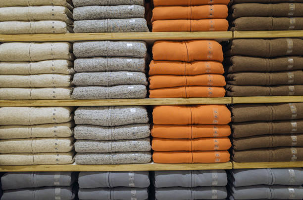 istock Stack of different color shirts on shelves in shop 1270862393