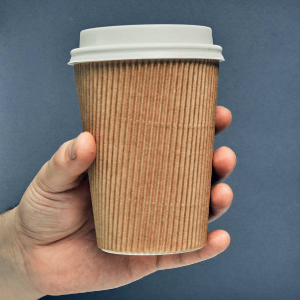 istock Paper cup in hand on a colored background. Eco-friendly materials in a coffee shop, biodegradable disposable tableware. Close up 1270868539