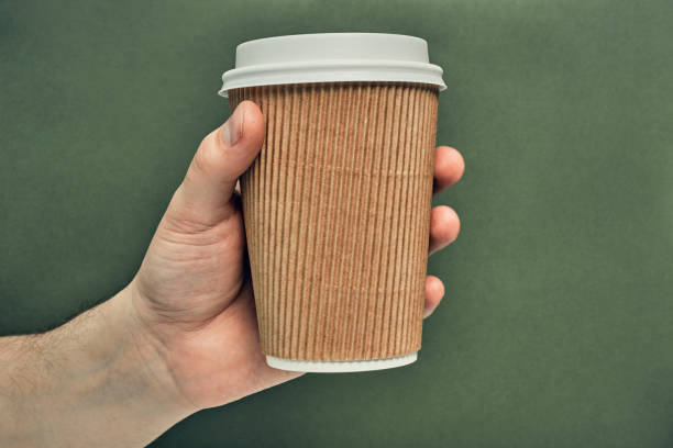 istock Paper cup in hand on a colored background. Eco-friendly materials in a coffee shop, biodegradable disposable tableware. Close up 1270868540