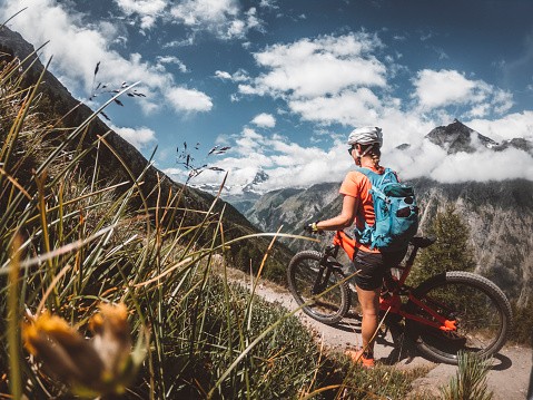 Woman mountain biking in Zermatt, Switzerland.  Female mountain biker riding around Swiss Alps on a summer day.