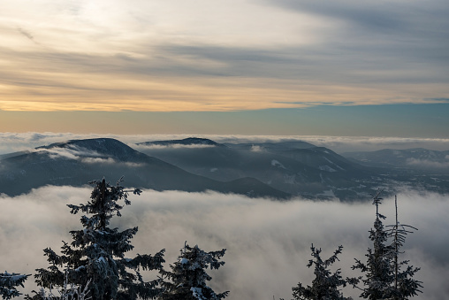 Smrk, Knehyne and Radhost hills from Lysa hora hill in winter Moravskoslezske Beskydy mountains in Czech republic with fog on lower altitudes and blue sky with clouds above