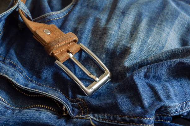 istock Close-up of blue jeans with a brown leather belt. 1270894012