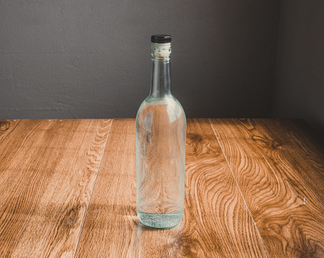 bottle with clear liquor. like mezcal, crystal tequila, or vodka. on oak planks