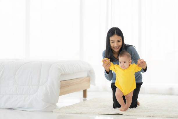 la mia bambina fa i primi passi. famiglia felice bambino piccolo imparare a camminare con l'aiuto della madre a casa - steps baby standing walking foto e immagini stock