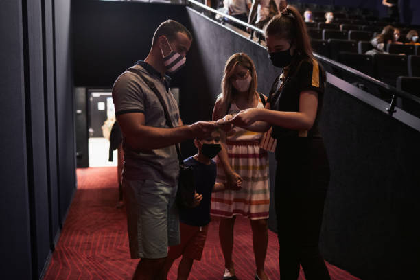 reapertura del cine después de coronavirus pandemia - familia hablando con el cine usher - acomodador fotografías e imágenes de stock