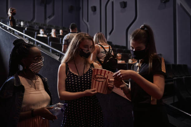 reapertura del cine después de la pandemia de coronavirus - dos mujeres jóvenes que hablan con el cine usher - acomodador cine fotografías e imágenes de stock