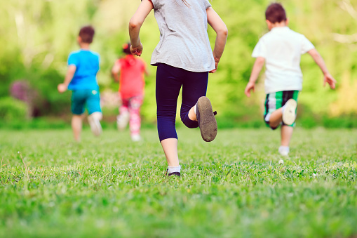 Many different kids, boys and girls running in the park on sunny summer day in casual clothes
