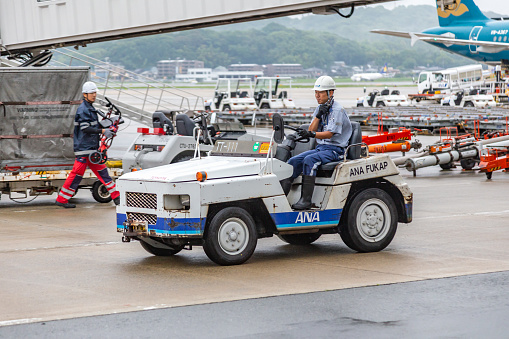 Fukuoka, Japan - 14 July 2019 - Airport baggage handler drives a baggage truck puller at Fukuoka airport in Japan on July 14, 2019