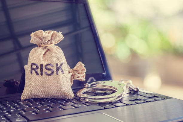 istock Bag with a word RISK and a handcuff on a laptop computer 1270910047