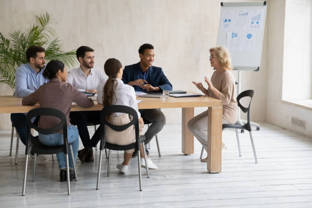 istock Smiling older mature boss instructing motivating diverse colleagues. 1270913480