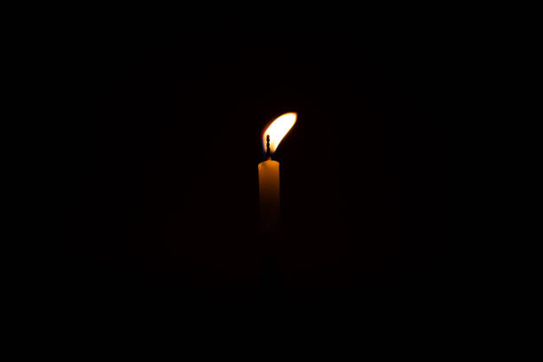 istock Close up single burning, bright white paraffin candle light on isolated dark black background. Red, orange, yellow candle fire flame smoke in party festival celebration at night. Copy space for text. 1270914796
