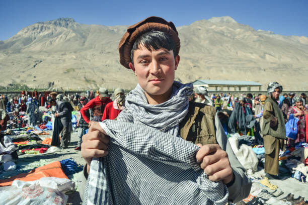 guapo joven pastún afgano sonríe sosteniendo bufanda en el mercado afgano - asia central fotografías e imágenes de stock