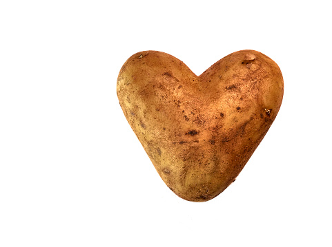 Directly from above picture of a heart shaped potato in front of a white background in Germany