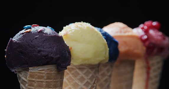 Row of multi colored ice cream cones on black background. Close-up