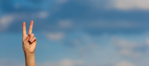 istock Woman hand over clouds background. Doing the victory gesture 1270921285