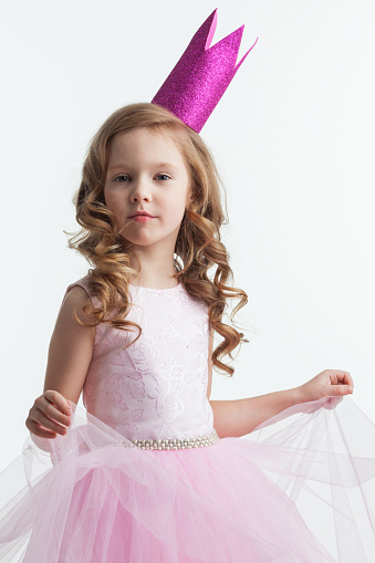 Little cute girl posing in pink halloween princess costume and crown isolated on white background