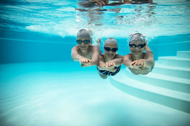 istock Three happy kids swimming underwater in pool 1270921733