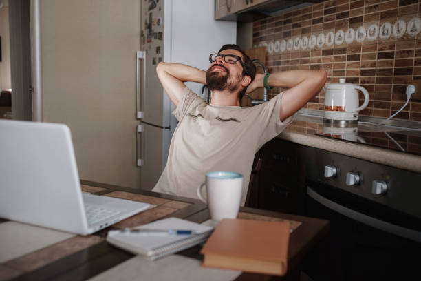 istock Smiling hipster freelancer holding hands behind head sitting at office desk behind laptop 1270921794