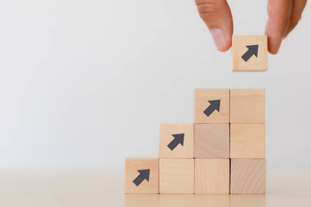 istock business growth go success progress process concept. business man hand arranging wooden cube block with grow up 1270926051
