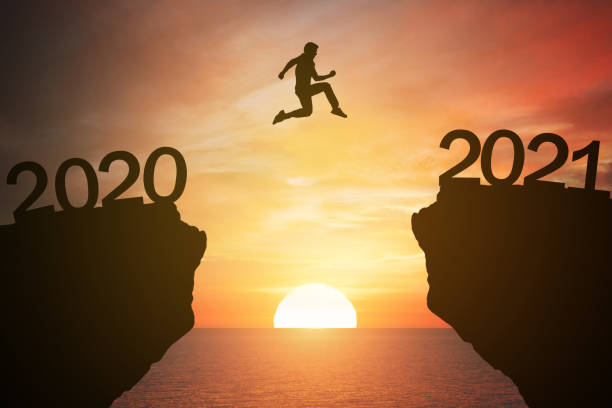 silhouette hombre saltar de la montaña de 2020 a 2021 años con el atardecer o el fondo del amanecer. feliz y éxito crecimiento con el concepto de año nuevo 2021 - intend fotografías e imágenes de stock