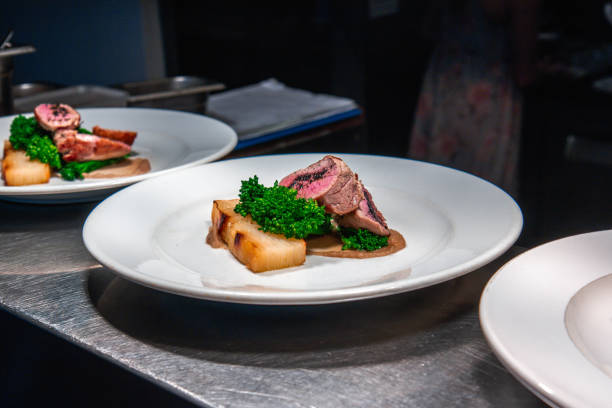 three plates close up roast beef dinners on neutral background in restuarant kitchen environment