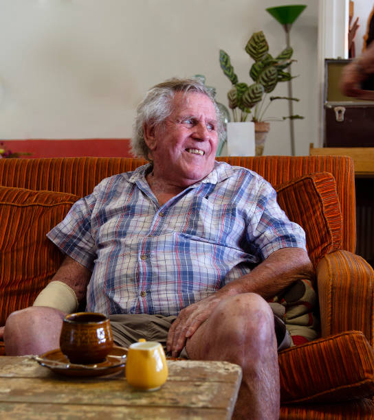 Happy senior man looking to his left while sitting on a couch in Queensland, Australia