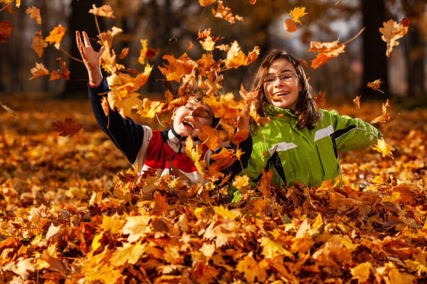 istock Girl and boy throwing up leaves in park 1270929310