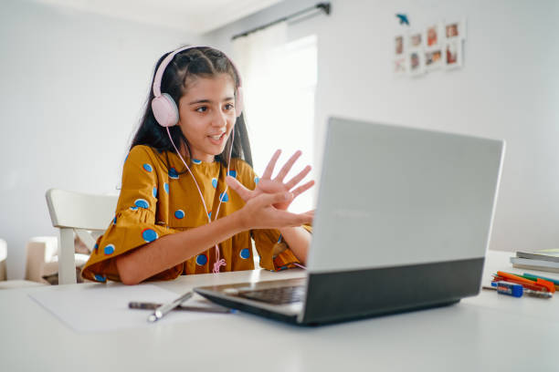 teenage girl with headphones and laptop having online school class at home - online education imagens e fotografias de stock