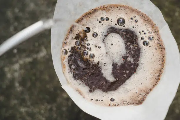 top down landscape shot of water pouring into swirling bubbling coffee grounds filter coffee process