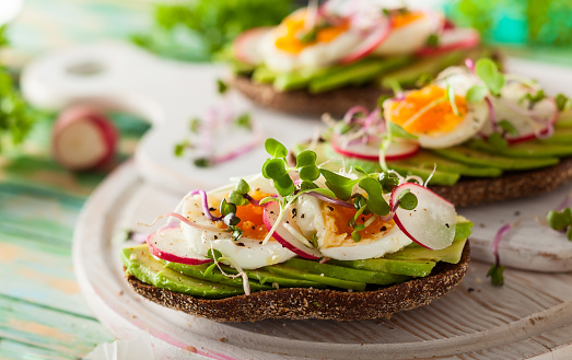 Open sandwiches with avocado,radish, boiled egg and sprouts. Concept of healthy eating or vegetarian food.