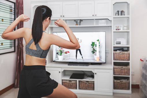 Home healthy exercise concept, Asian fit woman stay home and training online sport workout class on tv at home, New normal life of covid-19 outbreak