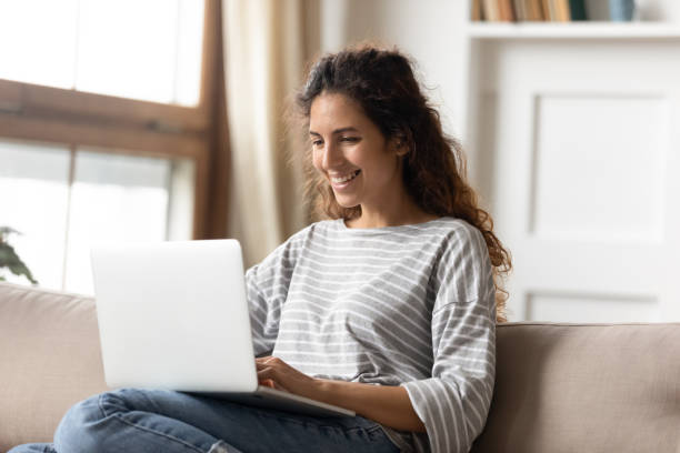 istock Woman smile sit on couch put pc on laps read pleasant news 1270939952